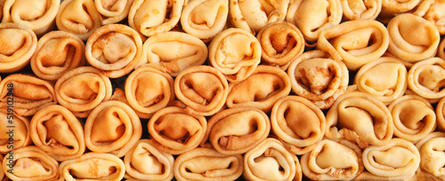 Stack of crepes rolls twisted with meat. Traditional Ukrainian russian thin pancakes as background. Tasty morning breakfast or lunch. Homemade food for maslenitsa. Banner. Close up view.