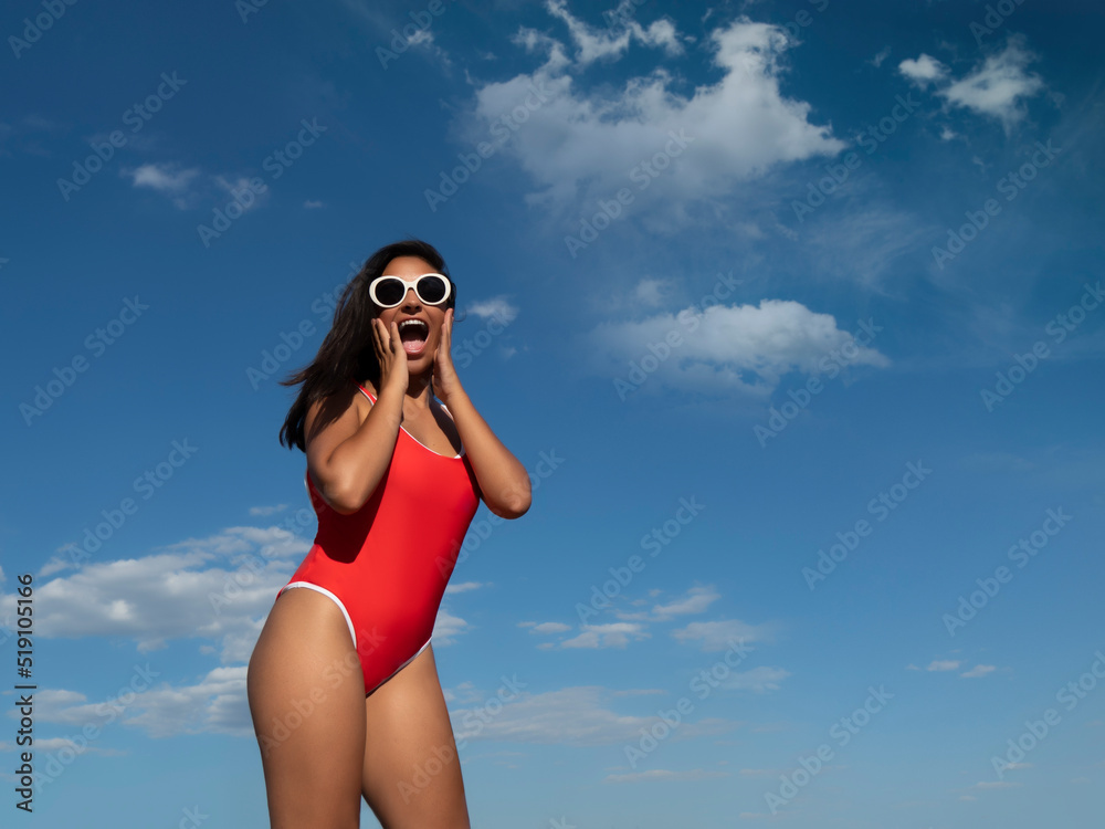 Amazed woman in swimsuit standing against blue sky Amazed woman in swimsuit standing against blue sky