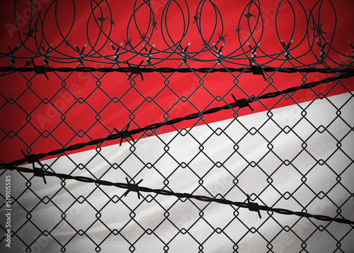 Indonesian flag behind barbed wire and metal fence