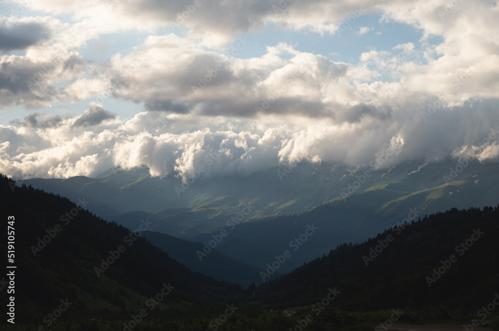 Mountain forest gorge landscape, clouds cling to the tops of high mountains, a glimpse of the sun's rays