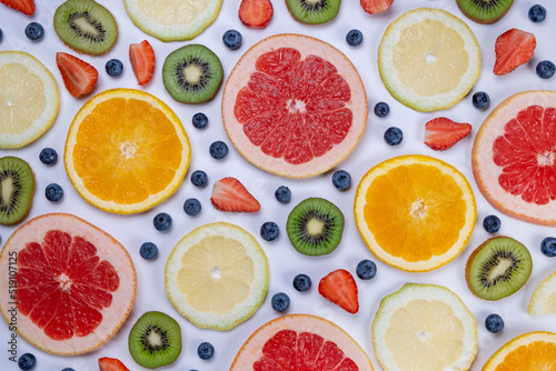 background of blueberries, strawberries, lemon, orange, grapefruit and kiwi slices on a white background - the concept of a healthy diet. Summer bright food fruit background, food design