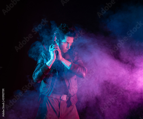 A guy in a cyberpunk image, holding a gun in his hands. Futuristic character in smoke. A young man in neon lighting on a black background