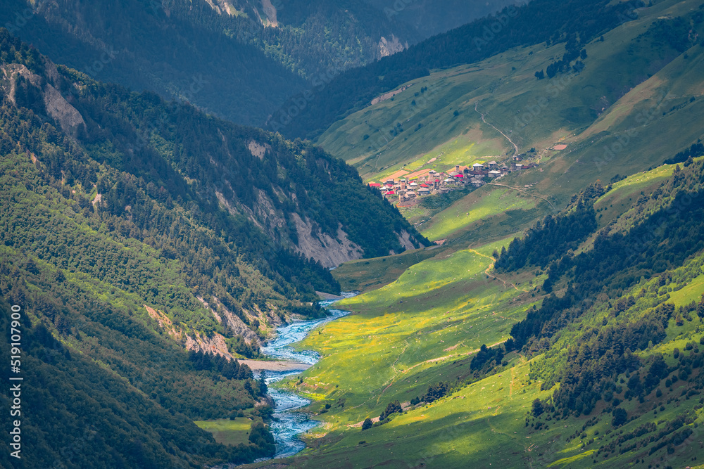 Long focus picture of Adishi village in deep mountain canyon. Splendid summer scene of Upper Svaneti, Georgia. Beautiful morning landscape of Caucasus Mountains. Traveling concept background..