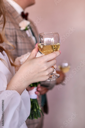 Bride and groom standing holding wine glasses. Wedding celebration.