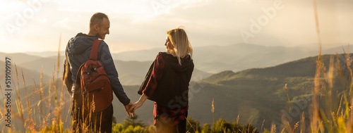 Happy traveler young couple resting in the mountains at sunset in spring or summer season.