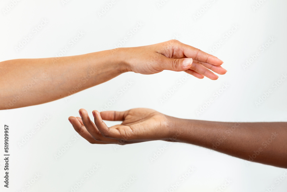 Hands with different skin colour, one african-american, one caucasian, touching each other on gary background.