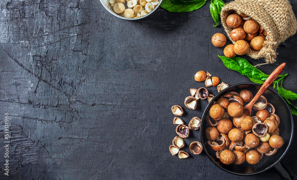 Organic dry Macadamia nut in a brown sack on black wooden background Organic dry Macadamia nut in a brown sack on black wooden background