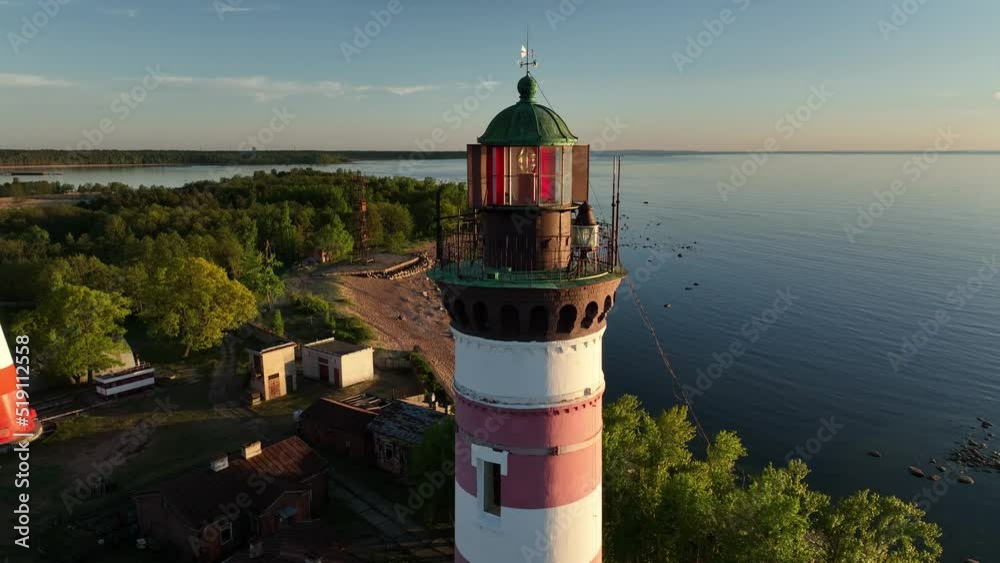Aerial view of the Close-up tower lighthouse at sunset. Drone view of the sea lighthouse on the bay Aerial view of the Close-up tower lighthouse at sunset. Drone view of the sea lighthouse on the bay