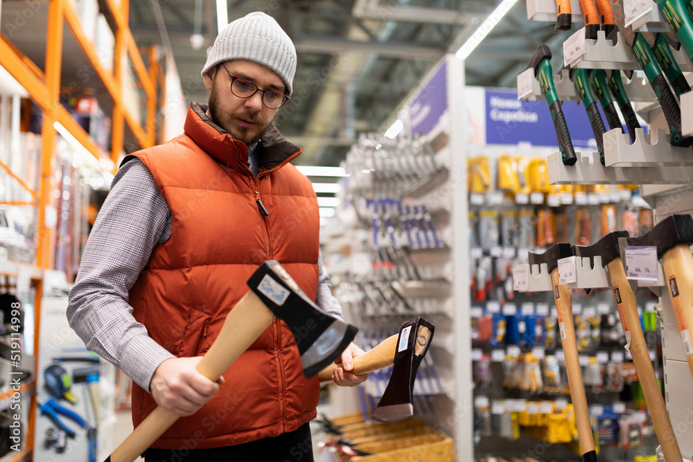 a man in a construction hypermarket chooses a household ax a man in a construction hypermarket chooses a household ax
