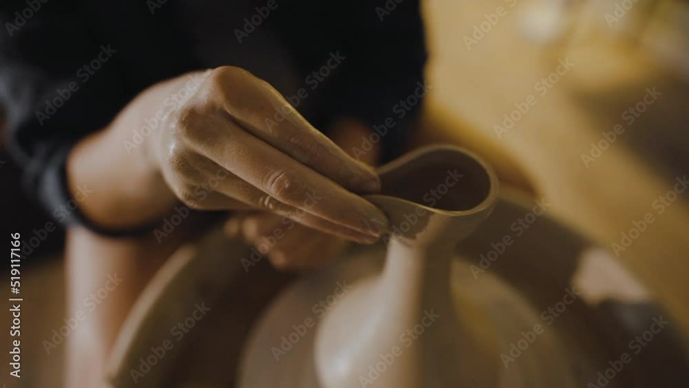 Female hands of a potter sculpt the spout of an earthenware jug from clay Female hands of a potter sculpt the spout of an earthenware jug from clay