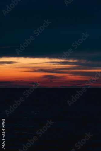 Dark sunset on the sea with orange flashes of light. Vertical photo © yaroslav1986