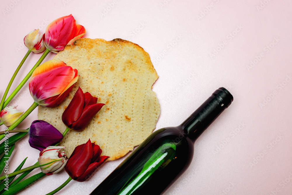 Bouquet of tulips, bottle of wine and matzo on a pink background