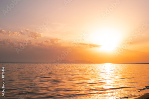 Colorful ocean beach sunrise with deep blue sky and sun rays. © netdrimeny
