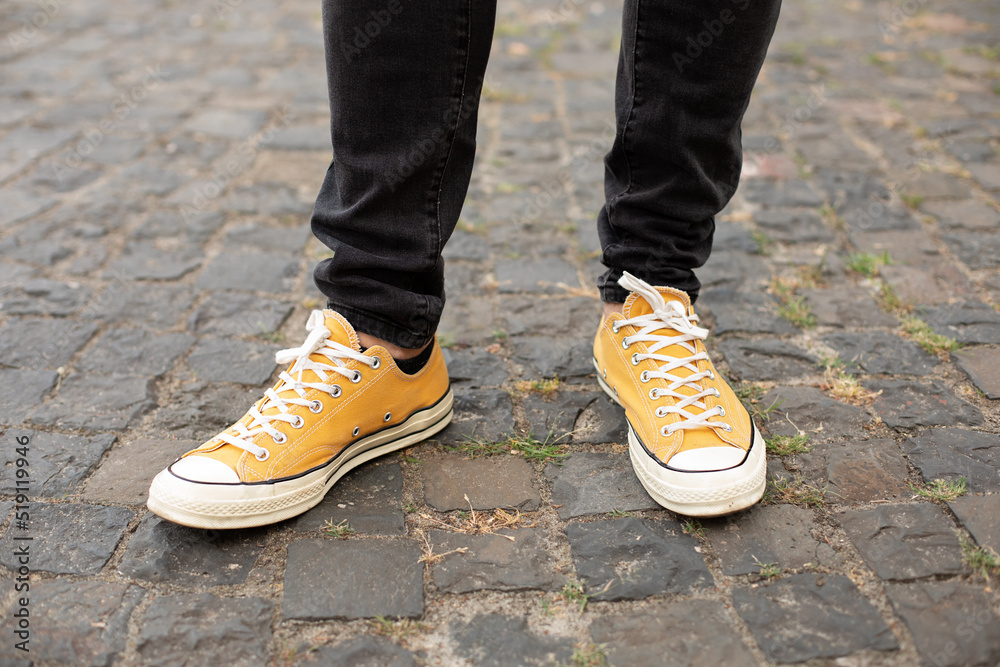 Male in yellow sneakers being walking down the street. Confident man Feet Walking In City. Man Legs In in shoes Walking on sidewalk. Close up Feet of man while walking commuting to work. 