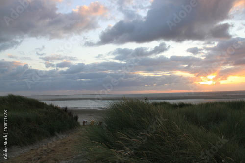 at the sea the red-golden sun shines out from behind the clouds before it sets