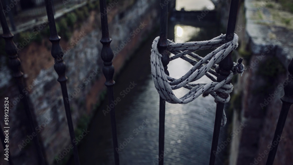 A lanyard tied to a handrail against a canal in the background