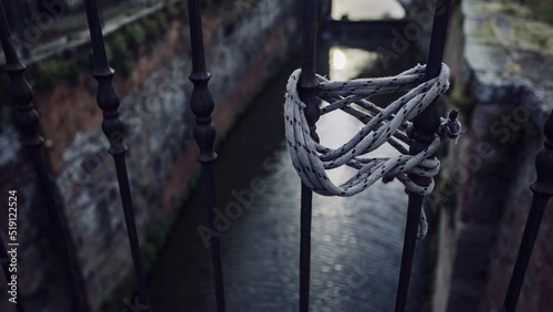 A lanyard tied to a handrail against a canal in the background