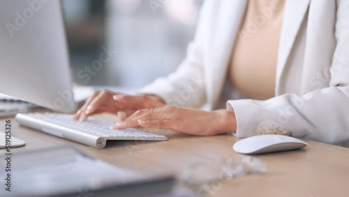 Closeup of a receptionist typing and sending emails while working in an office alone. One secretary doing admin and writing reports while organizing a schedule for her manager at work photo