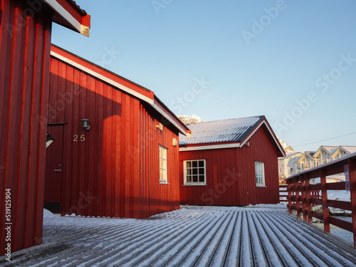 Three red wooden cabins of fishermans of Lofoten. Cold landscape of northern Norway, the rorbuers arre covered with snow at winter photo