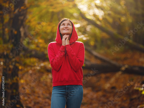 Travel and road trip concept at autumn. Adventure and active lifestyle in nature. Tourist hiking in forest. Asian woman in red hoodie walks in forest. Wanderlust concept. © YURII Seleznov