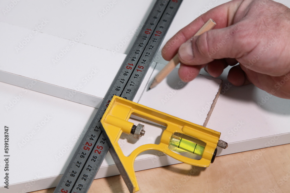 Carpentry marking angle rule and pencil in white hand on chipboard background closeup, DIY woodworking carpentry instrument