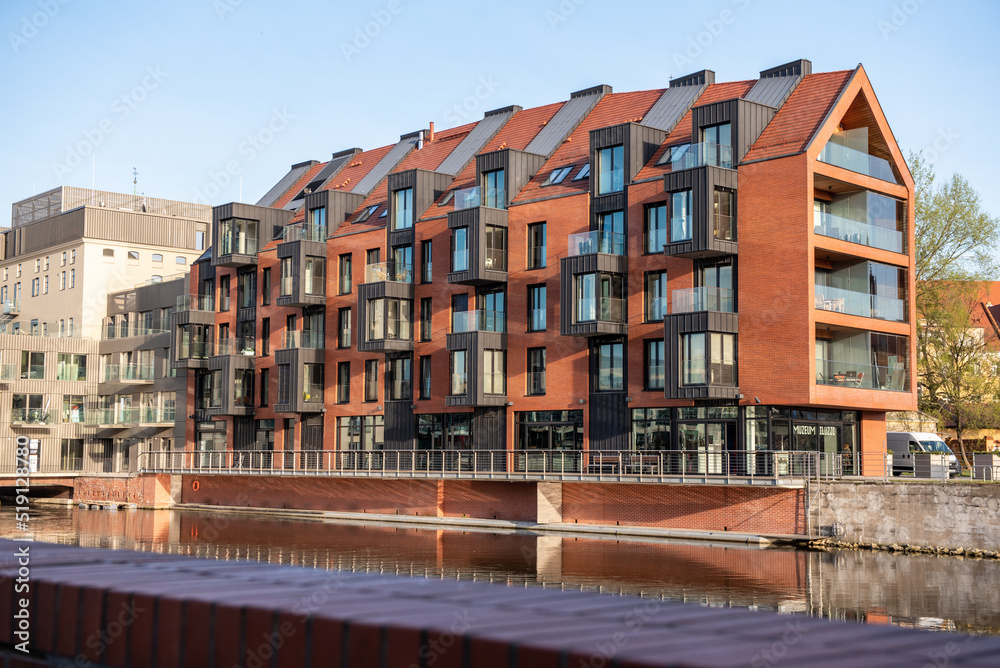 A beautiful modern high-rise building on the banks of the river. Brown brick building. Horizontal orientation. houses on canal country