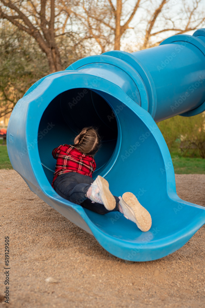 The girl rolls down the hill. Sliding down. Large children's slide-tube. children's playground. slider tube in playground The girl rolls down the hill. Sliding down. Large children's slide-tube. children's playground. slider tube in playground