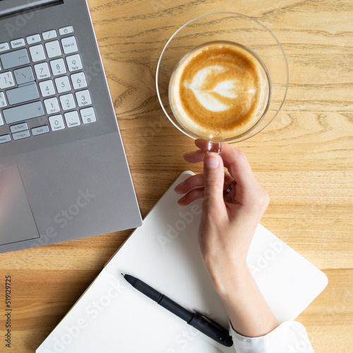 Beautiful hands in a white shirt with a cup of coffee laptop and notebook photo