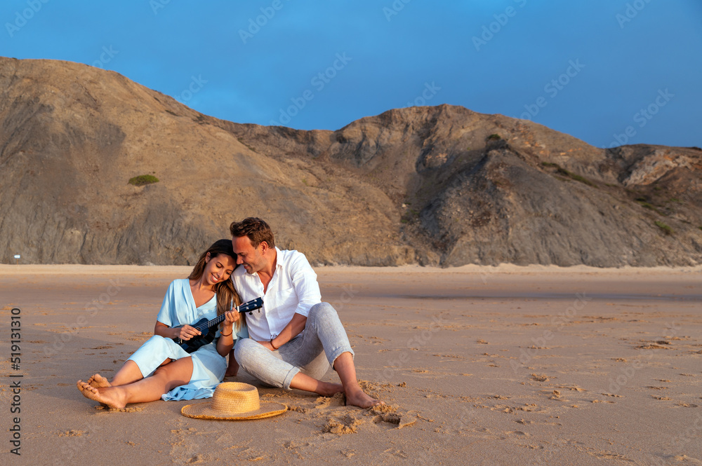 Cheerful couple with ukulele on seashore