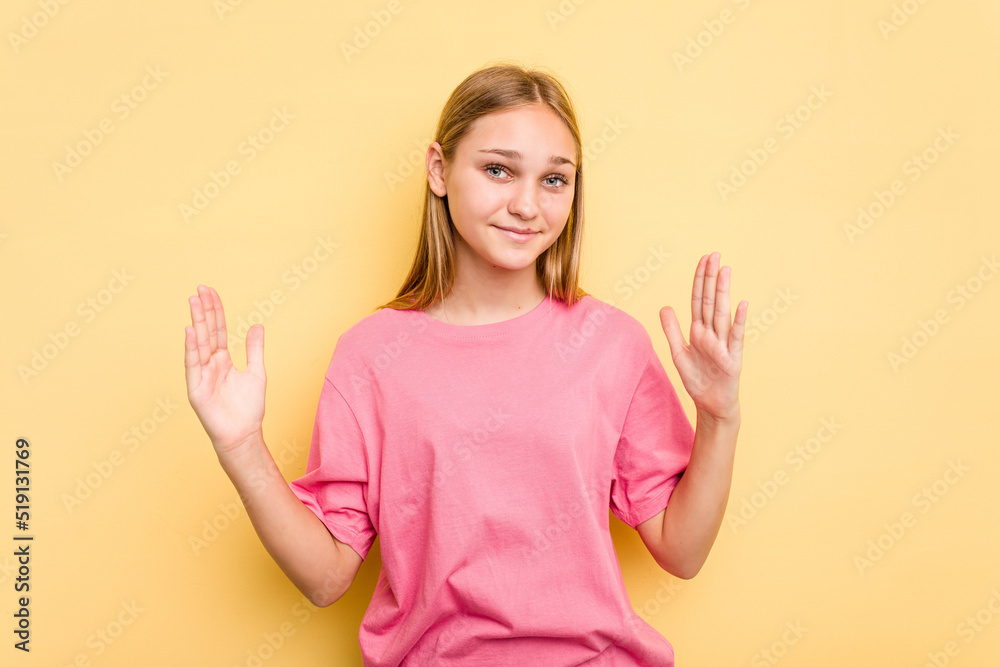 Young caucasian girl isolated on yellow background holding something little with forefingers, smiling and confident. Young caucasian girl isolated on yellow background holding something little with forefingers, smiling and confident.