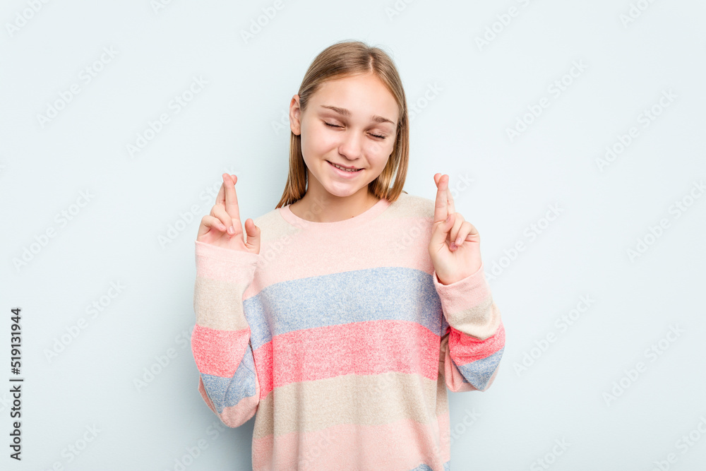 Young caucasian girl isolated on blue background crossing fingers for having luck Young caucasian girl isolated on blue background crossing fingers for having luck