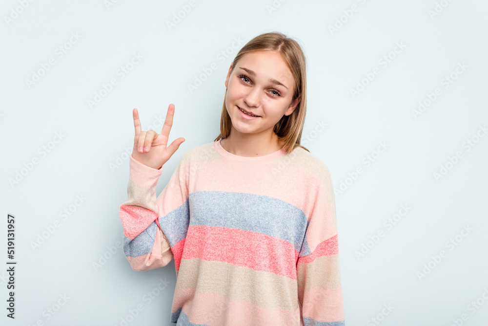 Young caucasian girl isolated on blue background showing a horns gesture as a revolution concept. Young caucasian girl isolated on blue background showing a horns gesture as a revolution concept.