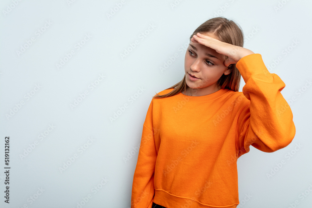 Young caucasian girl isolated on blue background looking far away keeping hand on forehead. Young caucasian girl isolated on blue background looking far away keeping hand on forehead.