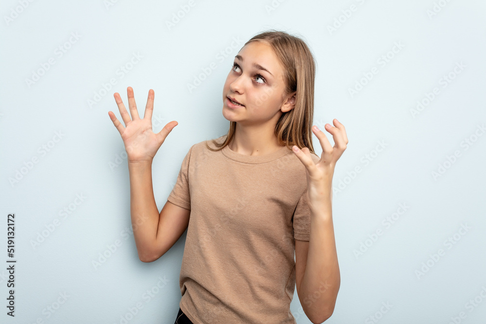 Young caucasian girl isolated on blue background screaming to the sky, looking up, frustrated. Young caucasian girl isolated on blue background screaming to the sky, looking up, frustrated.