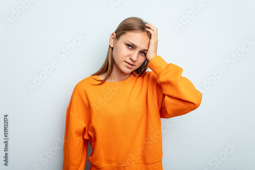 Young caucasian girl isolated on blue background forgetting something, slapping forehead with palm and closing eyes.