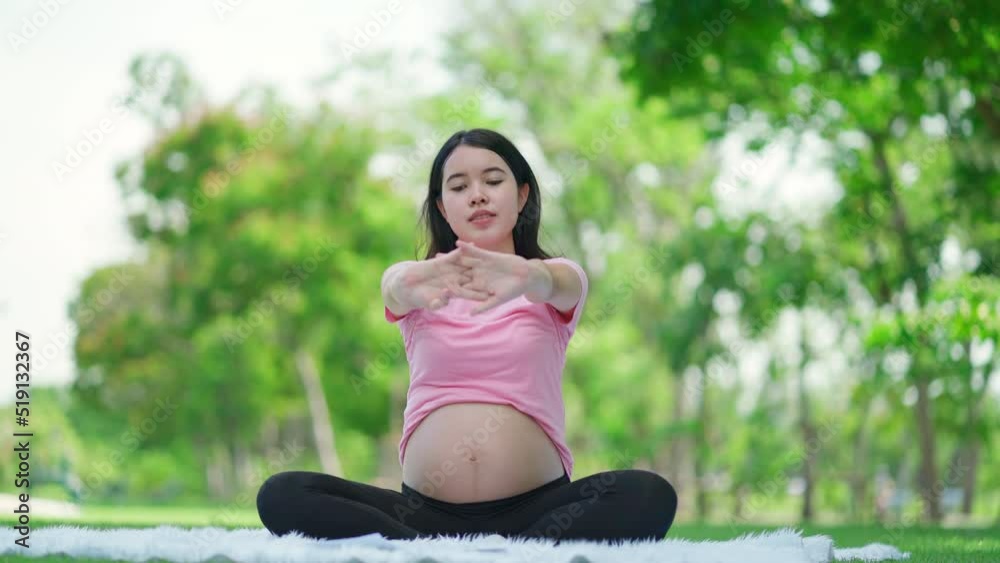 Asia beautiful pregnant woman sitting in the public garden doing yoga or exercise for health. Sport, fitness lifestyle while pregnancy. Workout in summer park doing exercise outdoor in meadow Asia beautiful pregnant woman sitting in the public garden doing yoga or exercise for health. Sport, fitness lifestyle while pregnancy. Workout in summer park doing exercise outdoor in meadow