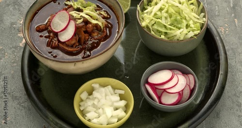 Vegan Pozole Rojo with toppings: shredded ice lettuce, radish and white onion. Famous pre-columbian  mexican dish made with cacahuazintle, shredded jackfruit, mushrooms and dried chilies. photo