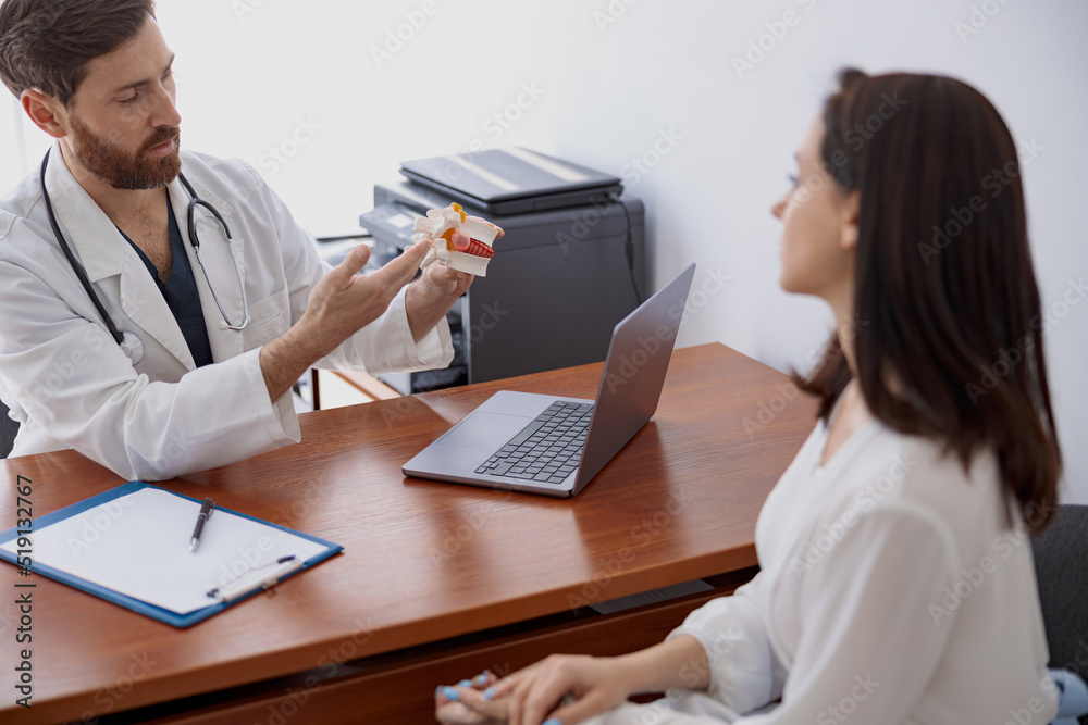 Male doctor consults patient and shows the model of several spines in modern clinic Male doctor consults patient and shows the model of several spines in modern clinic