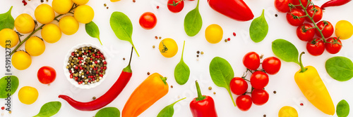 Yellow and red tomatoes, hot peppers, spinach and spices on a white background, food banner, top view