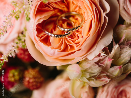 Fototapeta Naklejka Na Ścianę i Meble -  Wedding rings in white gold with a geometric pattern lie in a creamy peony rosebud.