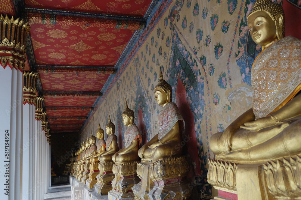 Gold Buddha statue gallery in temple at the colorful background, painted wall and ceiling 