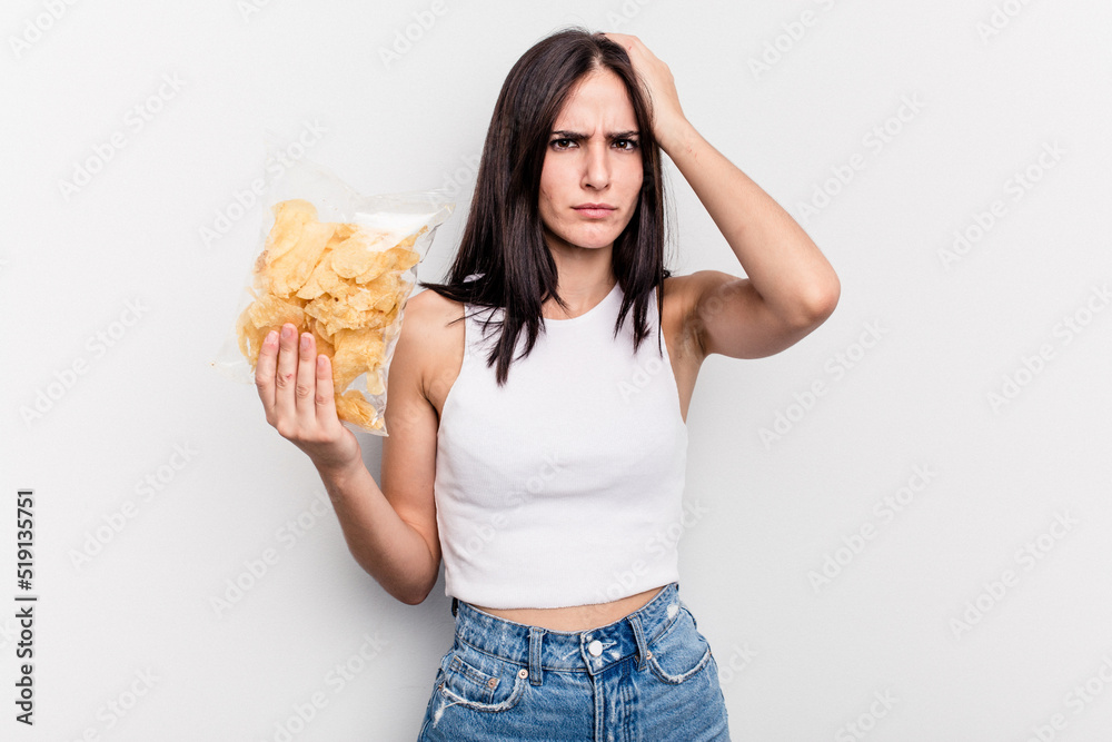 Young caucasian woman holding a bag of chips isolated on white background being shocked, she has remembered important meeting. Young caucasian woman holding a bag of chips isolated on white background being shocked, she has remembered important meeting.