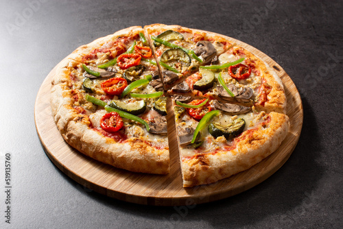 Vegetarian pizza with zucchini, tomato, peppers and mushrooms on black stone background 