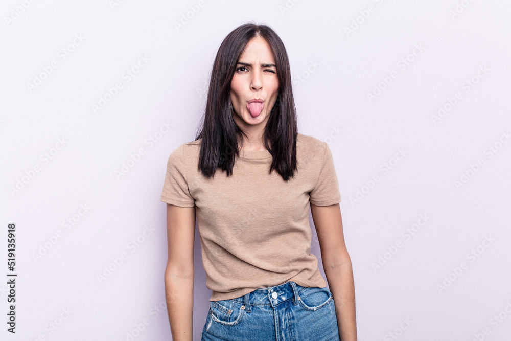 Young caucasian woman isolated on pink background funny and friendly sticking out tongue.