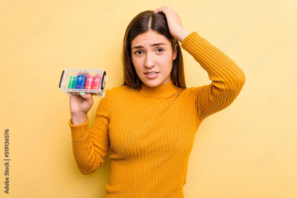 Young caucasian woman holding a batteries box isolated on yellow background being shocked, she has remembered important meeting. Young caucasian woman holding a batteries box isolated on yellow background being shocked, she has remembered important meeting.