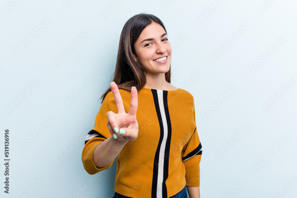 Young caucasian woman isolated on blue background showing victory sign and smiling broadly. Young caucasian woman isolated on blue background showing victory sign and smiling broadly.