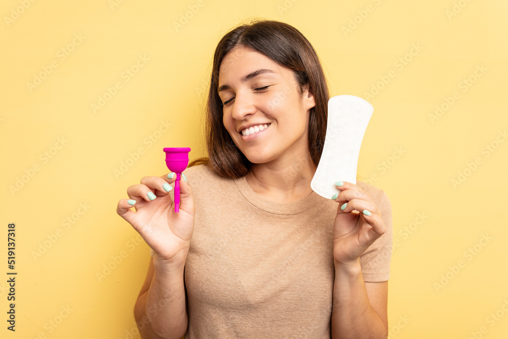 Young caucasian woman holding a menstrual cup isolated on yellow background Young caucasian woman holding a menstrual cup isolated on yellow background