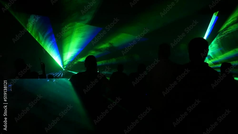 A modern laser light show, with a projection on smoke, a crowd of people watches the laser beams that turn into various lines and shapes. Outdoor performance. A modern laser light show, with a projection on smoke, a crowd of people watches the laser beams that turn into various lines and shapes. Outdoor performance.