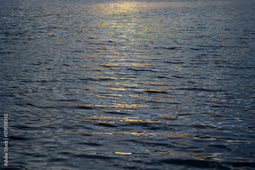 Water Surface of a River on a Sunset with Reflections. Background of Lake Water Surface with Ripples and Sunlight at Sunset. Natural Water Texture. Background from Sea Waves. 