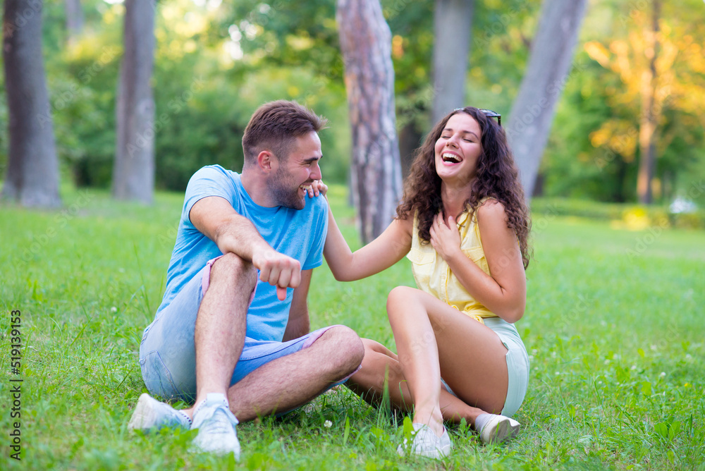 Young couple sitting in the grass of summer meadow Young couple sitting in the grass of summer meadow